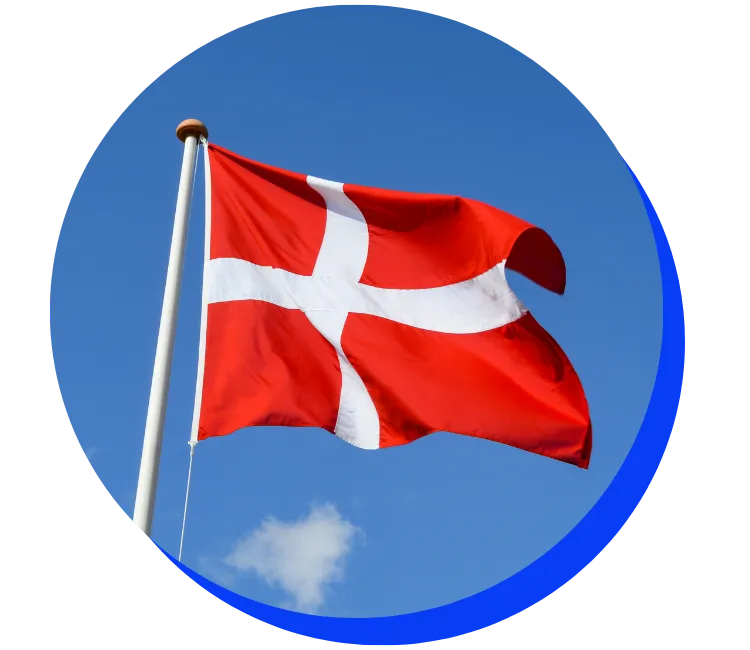 Danish flag waving in the wind against a blue sky with a small white cloud. The flag is red with a white Nordic cross.