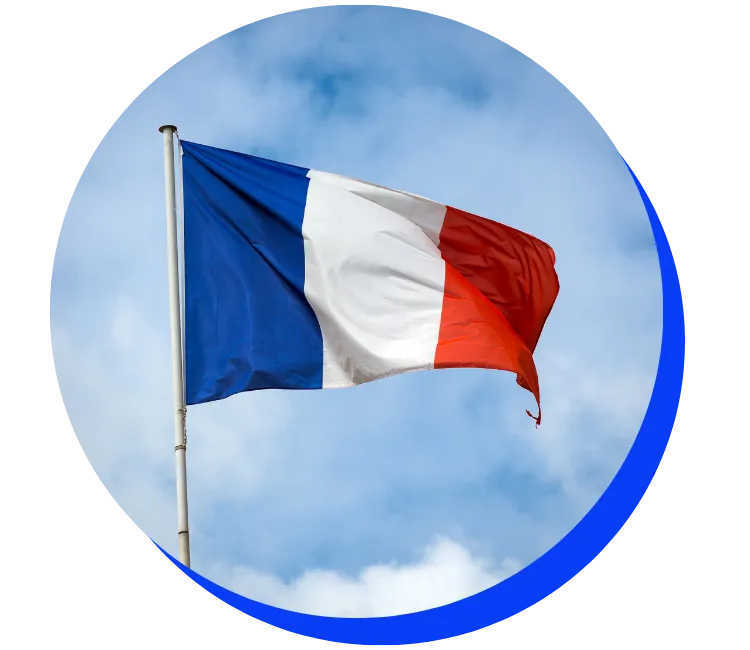 French flag waving against a cloudy blue sky. The flag features vertical stripes of blue, white, and red.