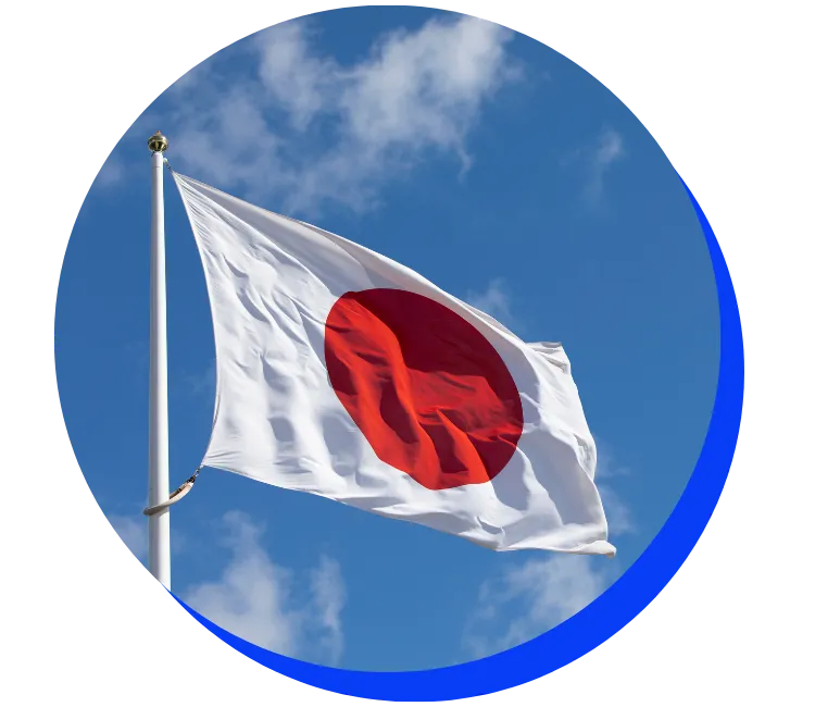 Japanese flag waving in a breeze against a blue sky with white clouds. The flag is white with a large red circle in the center.