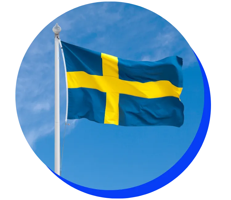 Swedish flag fluttering in the wind against a blue sky with light clouds. The flag has a yellow cross on a blue background, displayed within a circular frame with a blue border.